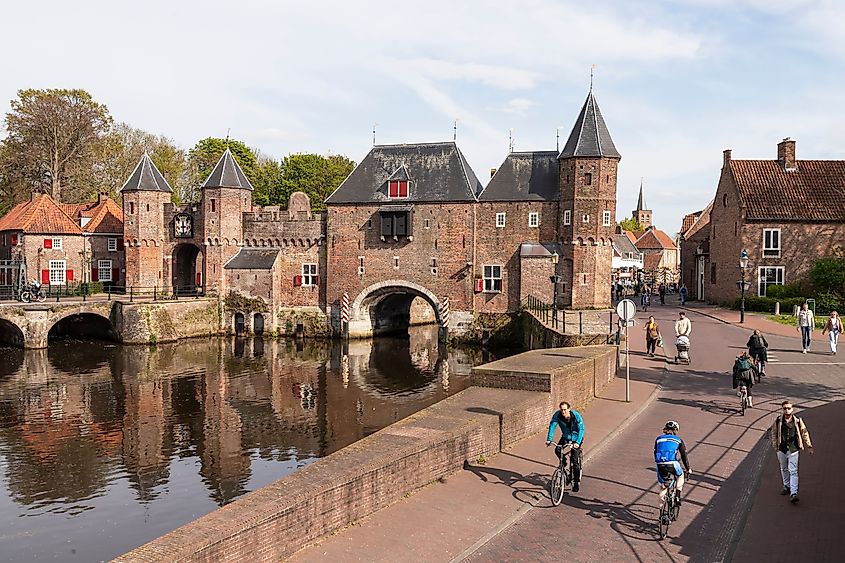 People walking and cycling along the historic Koppelpoort water gate in Amersfoort.