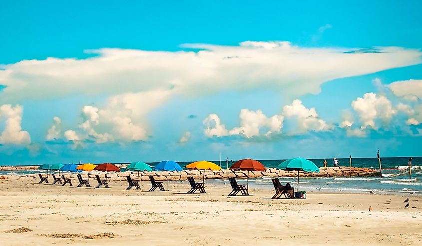 A row of colorful beach umbrellas and beach loungers on Galveston Island, Texas.