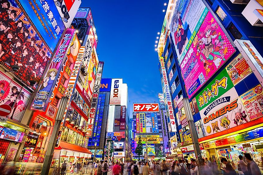 Crowds pass below colorful signs in Akihabara. The historic electronics district has evolved into