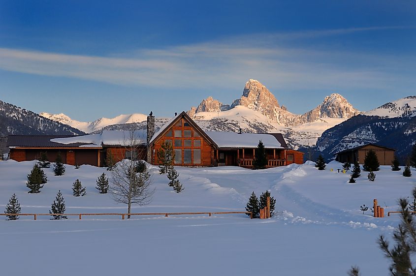 New house on a winter evening in Driggs, Idaho, USA, with Grand Teton peaks in Wyoming illuminated by the setting sun.