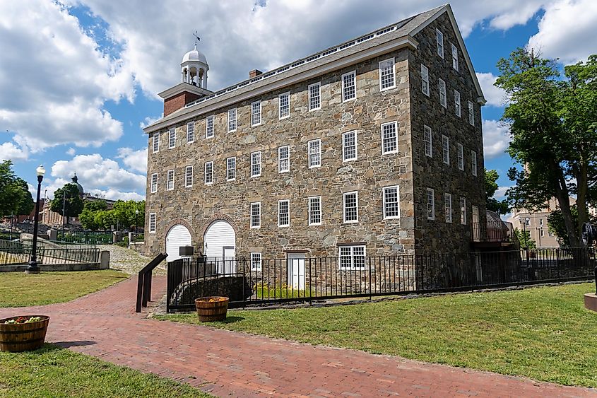 Pawtucket, Rhode Island -2022: Blackstone River Valley National Historic Park, Slater Mill Historic Site. The rubble stone Wilkinson Mill with steam power source - a steam engine built by Wilkinson.