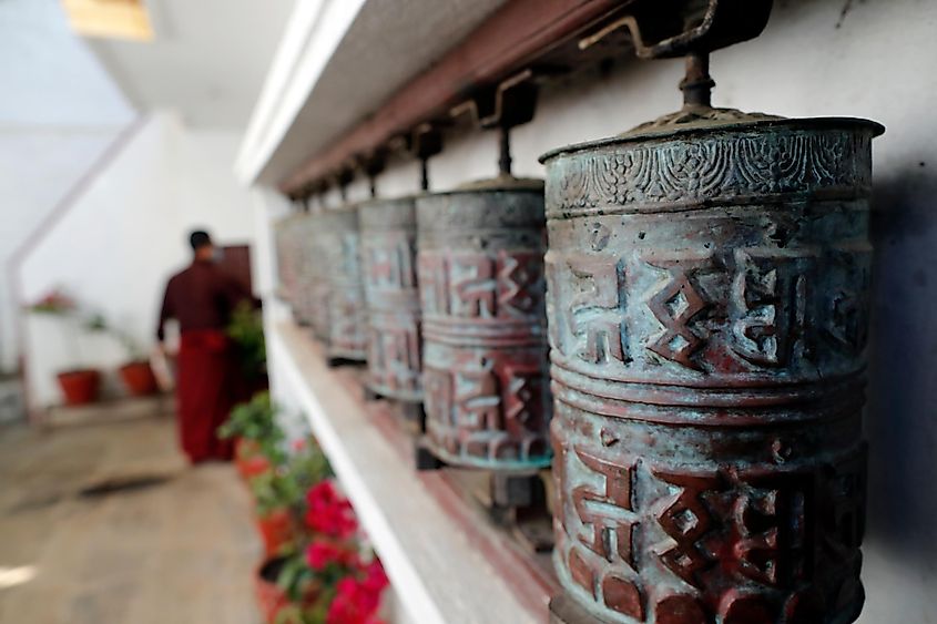 Pema Osel Ling Monastery. Rolling metal prayer wheels circling. A mantra is written in Tibetan language, on the outside of the wheel.