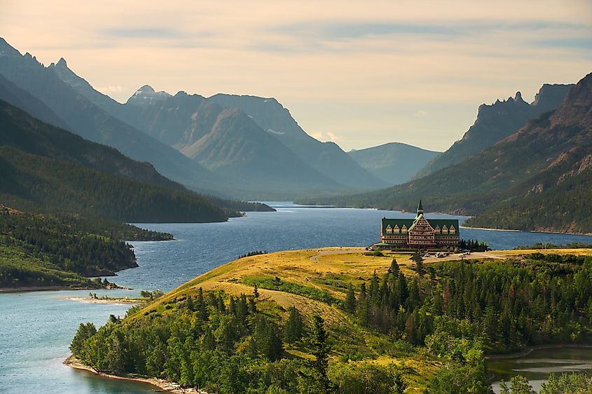 A view of Upper Waterton Lake during the early morning with a landmark Hotel building on a peninsular in the foreground.