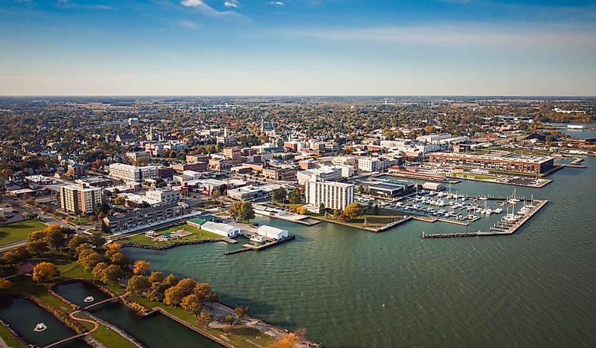 Boats sit idle docked to piers in a harbor along the coast just outside of downtown on a sunny autumn day, Sandusky, Ohio