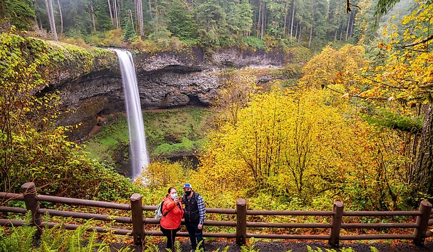 Two people taking selfie photos in front of South Falls at Silver Falls State Park near Silverton Oregon