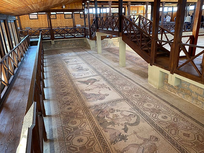 Floor boards above ancient floor mosaics depicting ancient Greek gods.