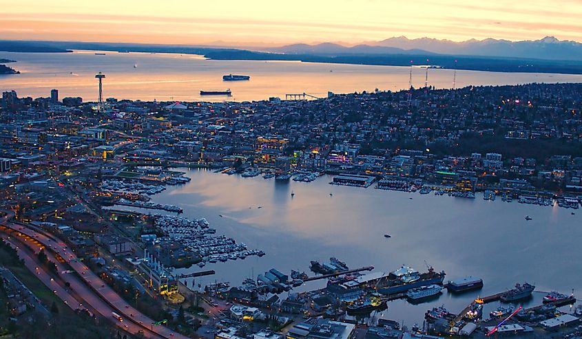 High above city of Seattle with Lake Union and Puget Sound, San Juan Islands Olympic Mountains Orange sunset sky glowing clouds ships ferry waterfront