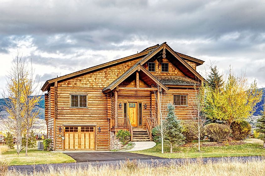 The exterior of a rustic log cabin nestled at the base of the majestic Teton mountain range in Driggs, Idaho