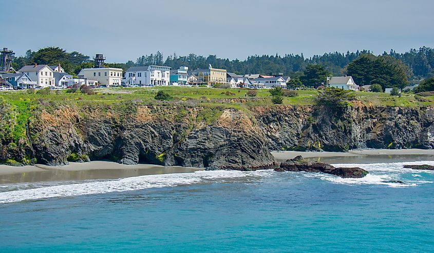 The seacoast village of Mendocino, California lines an ocean headland at low tide on a sunny spring afternoon