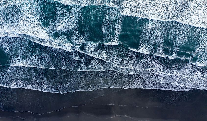 Aerial drone view of Atlantic ocean waves washing black basaltic sand beach, Iceland