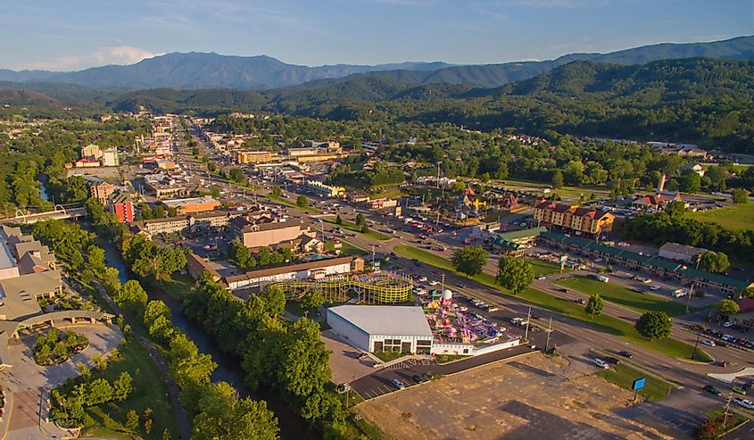 Drone, aerial, angled view of main strip, attractions, and mountains in Pigeon Forge, Tennessee