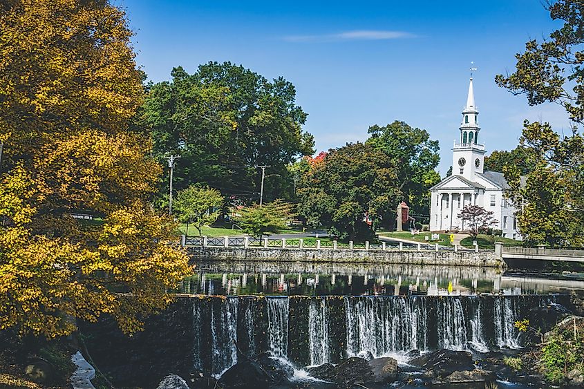 View of white church and waterfall surrounded by trees