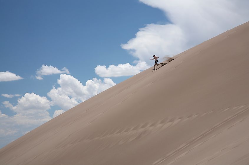 A visitor runs down a dune in Great Sand Dunes National Park.