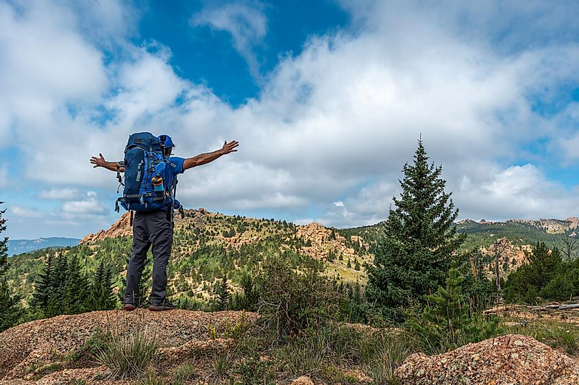 Backpacker holds up arms while looking into the landscape of the Lost Creek Wilderness in Colorado