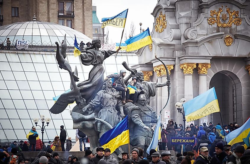 People sit on the monument decorated with flags in the center of Independence Square, Euromaidan Protests, Kiev.
