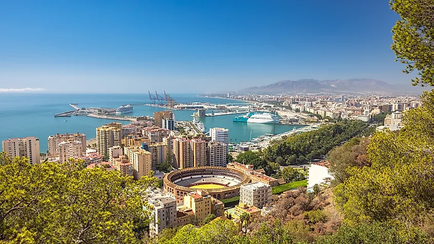 Malaga, seaside city in Andalusia, Spain, Europe. Coastal city skyline with harbor, buildings, and a bullring. A sunny day overlooking the Mediterranean.