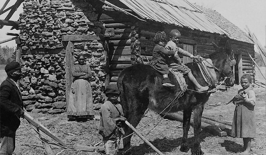 African American farm family outside their log cabin home in North Carolina.