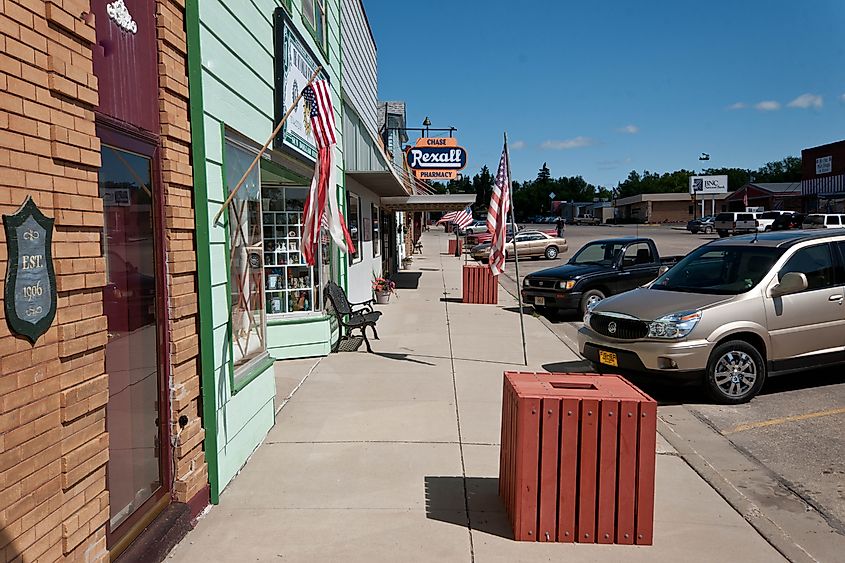 View from a sidewalk in Garrison, North Dakota, showcasing stores, cars, and the street.