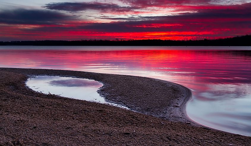 A horizontal image of sunrise on a sandy shoreline of Longview Lake. Longview Lake is located just outside of the Kansas City, Missouri area.