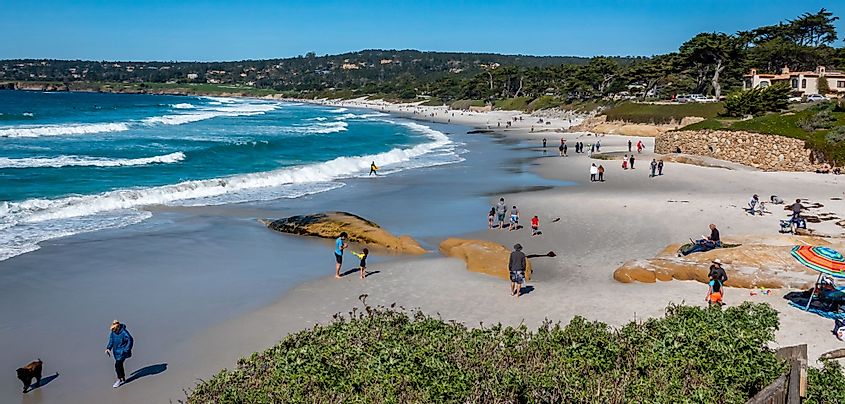 Tourists enjoy the sandy shores of Carmel Beach in Carmel-by-the-Sea, California