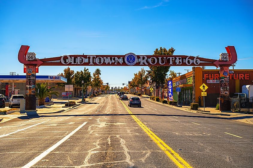 Vibrant street scene under the 'Old Town Route 66' neon archway sign in Victorville, featuring a clear blue sky and classic roadside attractions. Editorial credit: Nick Fox / Shutterstock.com