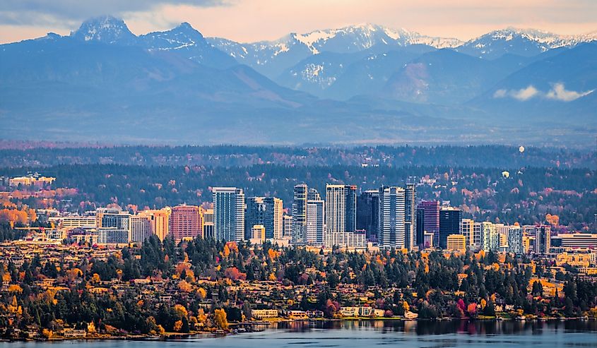 The snowy Alpine Lakes Wilderness mountain peaks rise behind the urban skyline, Bellevue, Washington