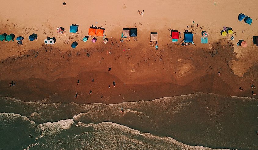 Aerial view of South  Padre Island beach.  Image shows the shore and colourful umbrellas shielding sun-bathers. 