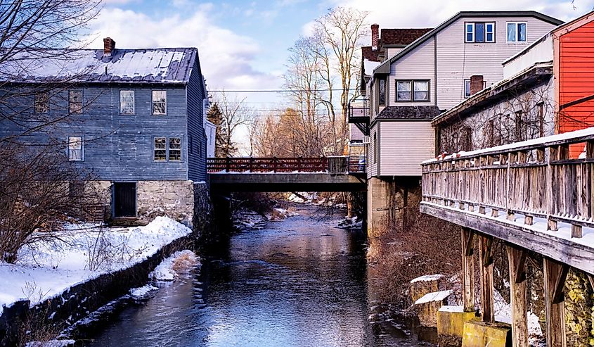 Old buildings lining the williams river running through the village of west stockbridge massachusetts on a sunny winter day.