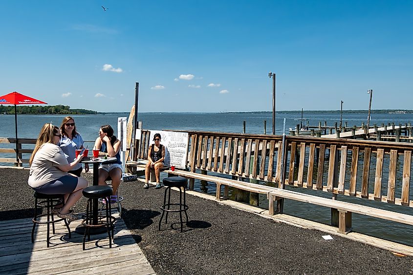 People sitting outdoors at an outdoor marina tiki bar on the Patuxent River in Mechanicsville, Maryland.