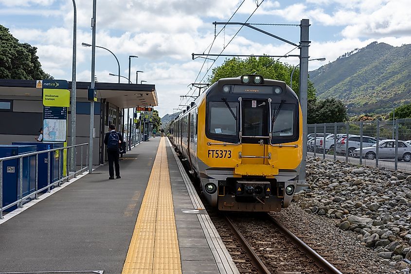 A close-up view of a yellow commuter train preparing to depart Waikanae Station in New Zealand.