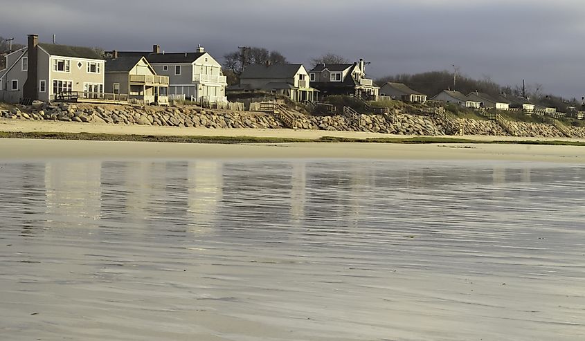 Beach landscape with long retaining wall near sunset across reflective tidal flats of Brewster, Massachusetts