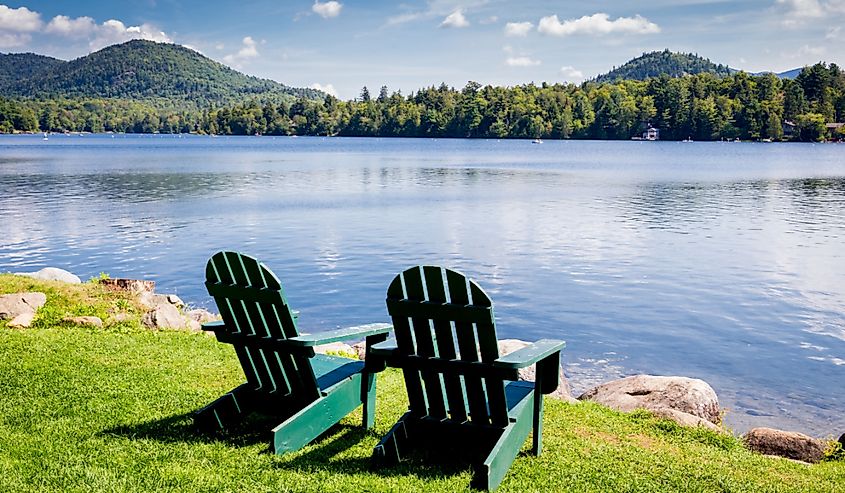 Adirondack chairs by the water in Mirror Lake, Lake Placid New York.