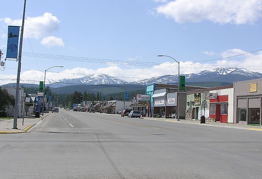 The street view of Libby, Montana, showcases charming shops nestled against a backdrop of snow-capped mountains, creating a picturesque scene.