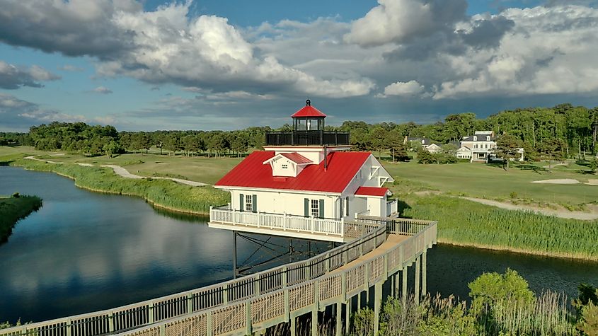 Lighthouse-style house at Bay Creek in Cape Charles, Virginia, on a pier over calm water.