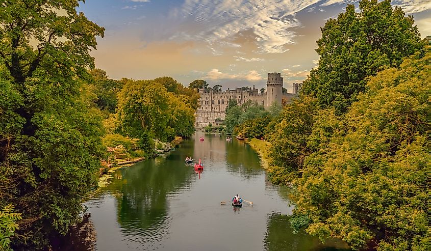 People in boats in the river in front of Warwick castle in England UK