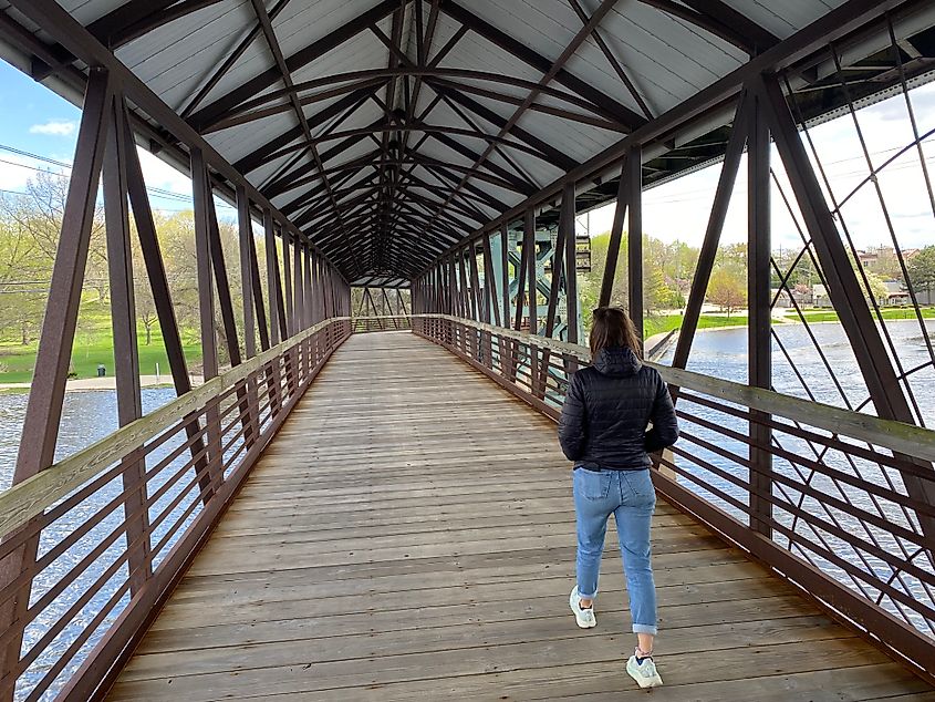 A woman walks across an old rail river bridge, now retrofitted for pedestrians only.