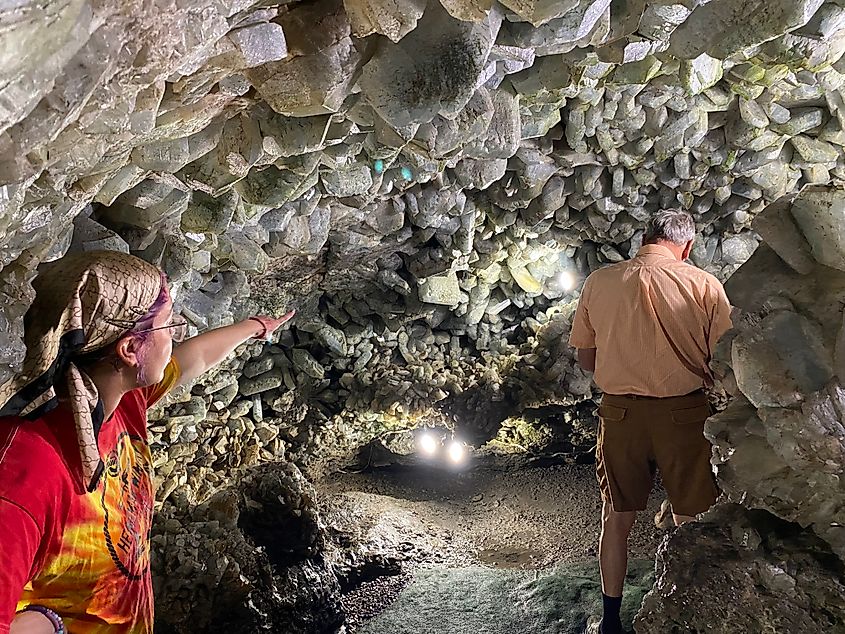 A woman points at the crystals inside of a massive geode. So big you can walk through it like a cave. 