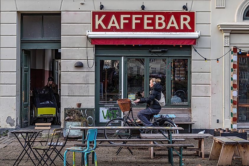 Copenhagen, Denmark Feb 4, 2023 A woman bikes by a vintage coffee shop in the Norrebro district.