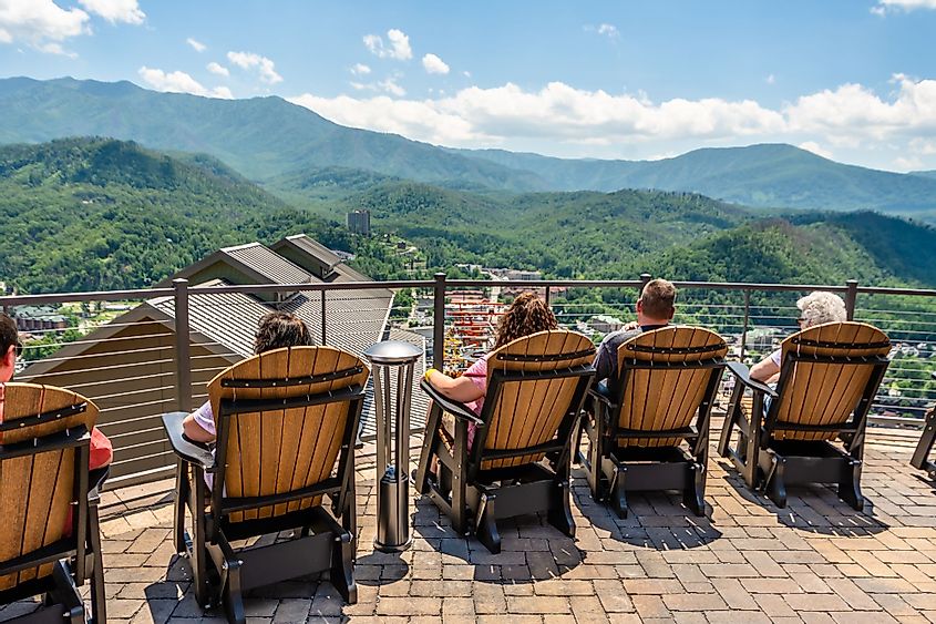 Tourists sit on the outdoor chairs at Gatlinburg Skydeck, facing the best view of the Great Smoky Mountains on a sunny day.