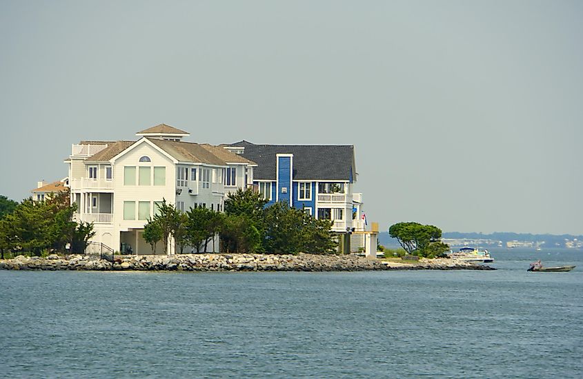 Waterfront houses along the rocks near Indian River Inlet in the summer, via Khairil Azhar Junos / Shutterstock.com