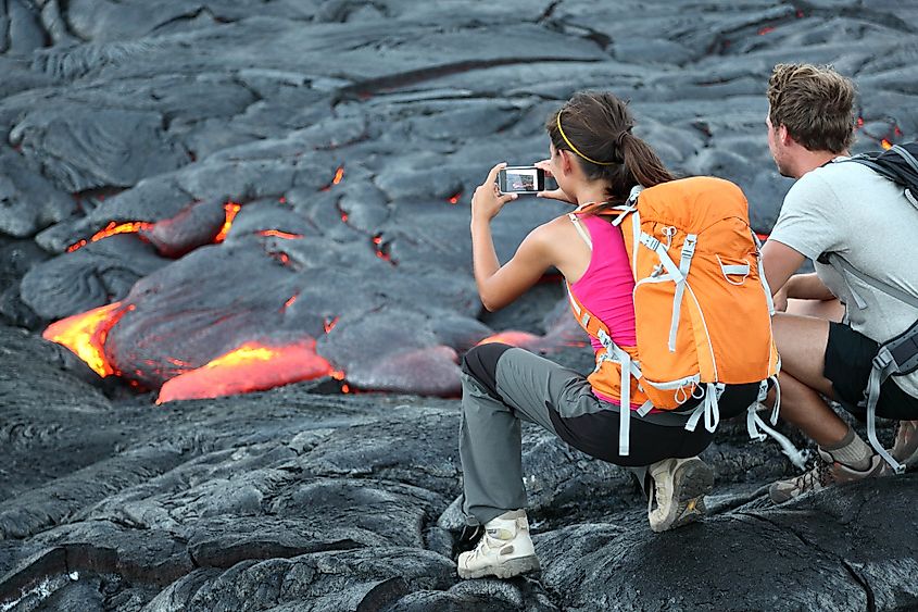Tourists taking photo of flowing lava from Kilauea volcano