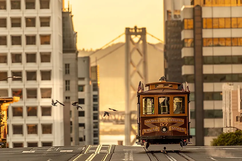 Top of the Nob Hill looking East towards a Bay Bridge tower with the San Francisco Van Ness Cable Car at dawn. Via Shutterstock / Jason Doly