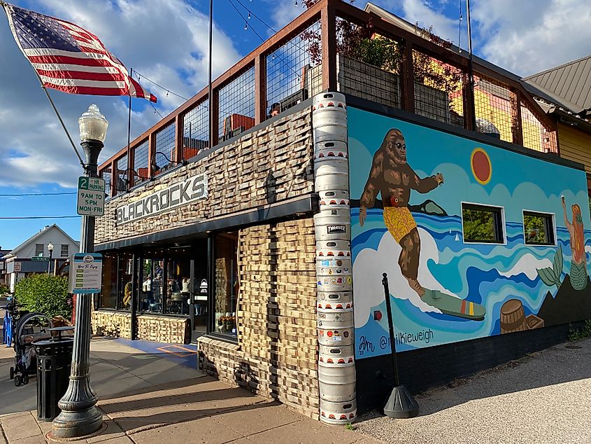 A two-story brewery with an American flag and surfing Bigfoot mural out front.