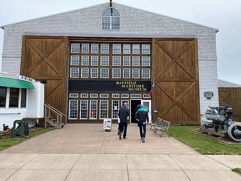 A group of people walk into a large hanger where the Bayfield Maritime Museum operates.