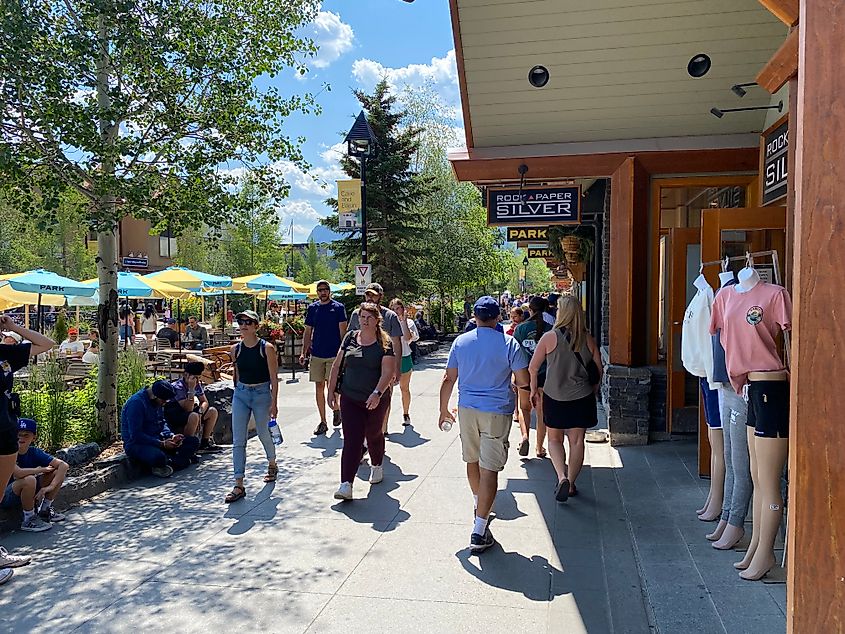 A steady crowd passes by main street shops and plunks beneath the streetside patio umbrellas. 
