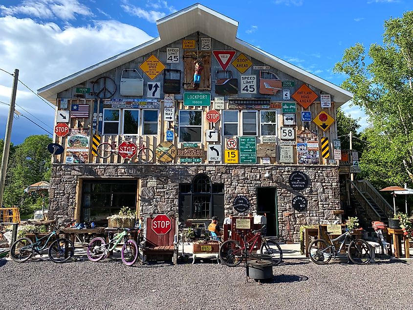 Cyclists chilling outside of a quirky accommodation covered in road signs.