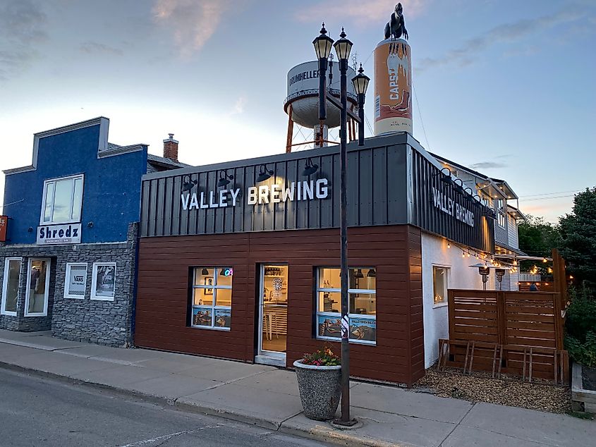 The shiny exterior of Valley Brewing in Drumheller, AB. A large novelty beer can with a velociraptor statue stand atop the roof.