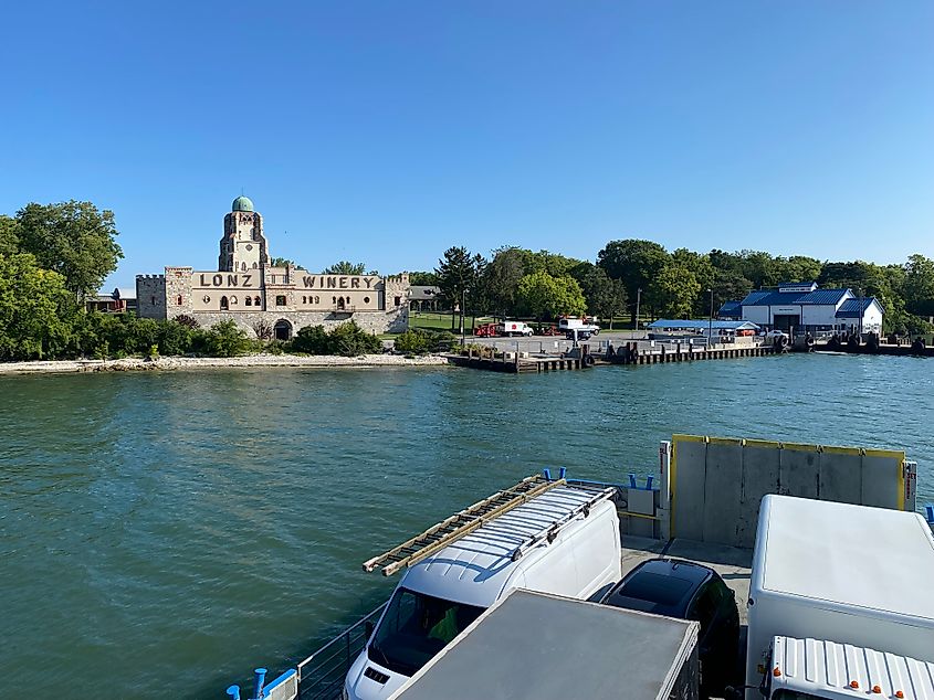 A ferry full of trucks approaches the dock and a stately building branded: Lonz Winery. 