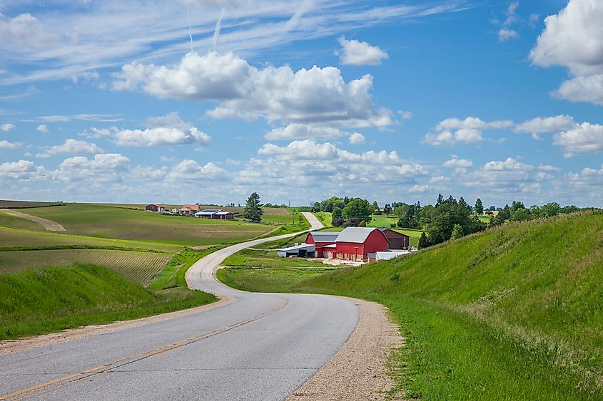 Farm with a red barn on a curving road in the Iowa countryside on a beautiful spring day.