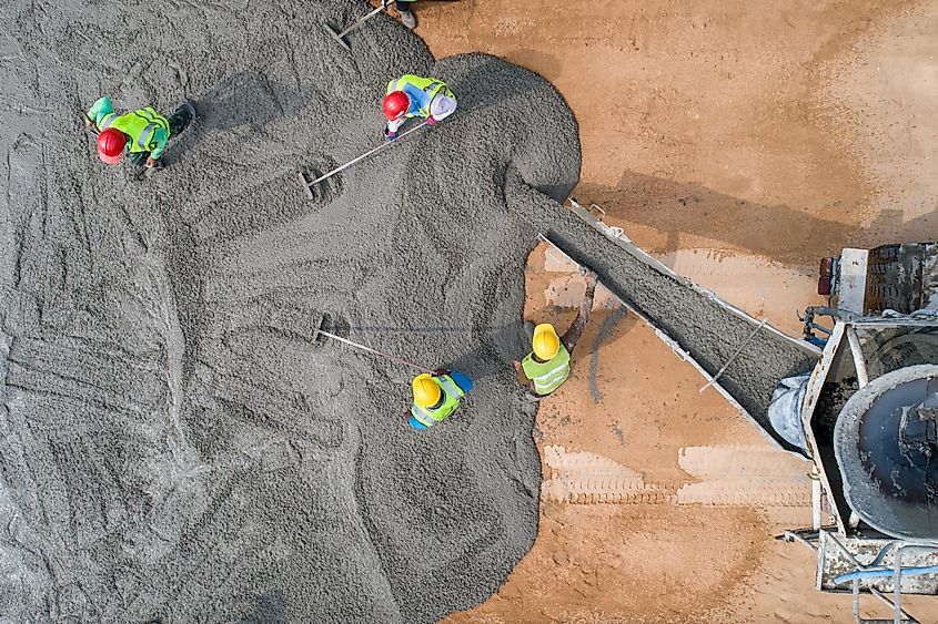 A construction worker pouring a wet concret at road construction site